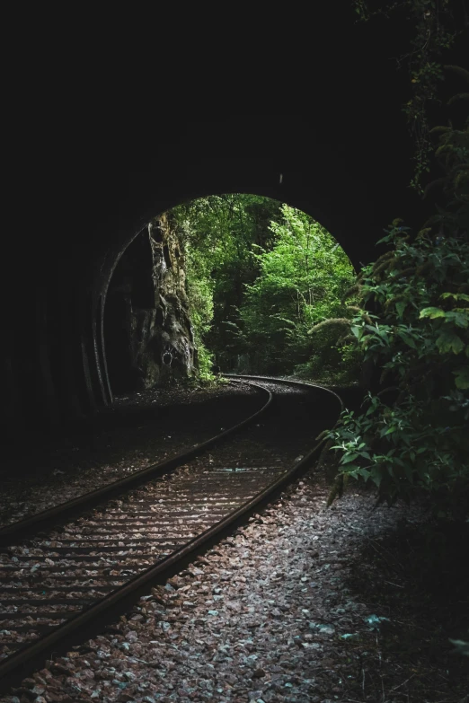 light shining on a train track at the end of a tunnel