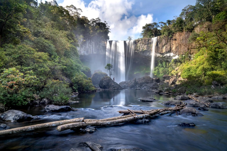 some water and trees by a tall waterfall