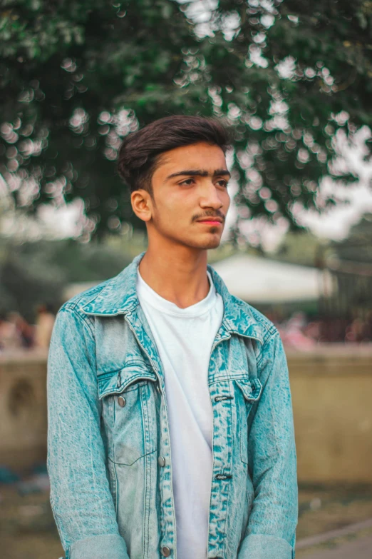 a man wearing a jean jacket poses for the camera