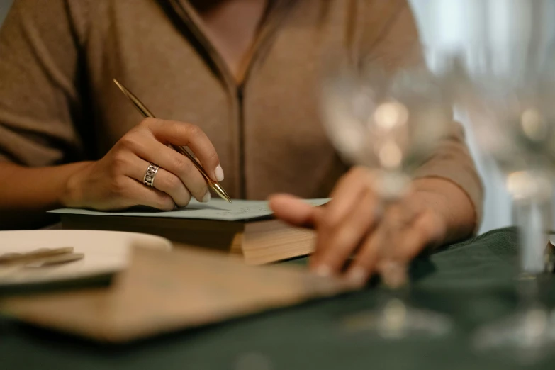 a woman is writing on a notepad and wine glasses