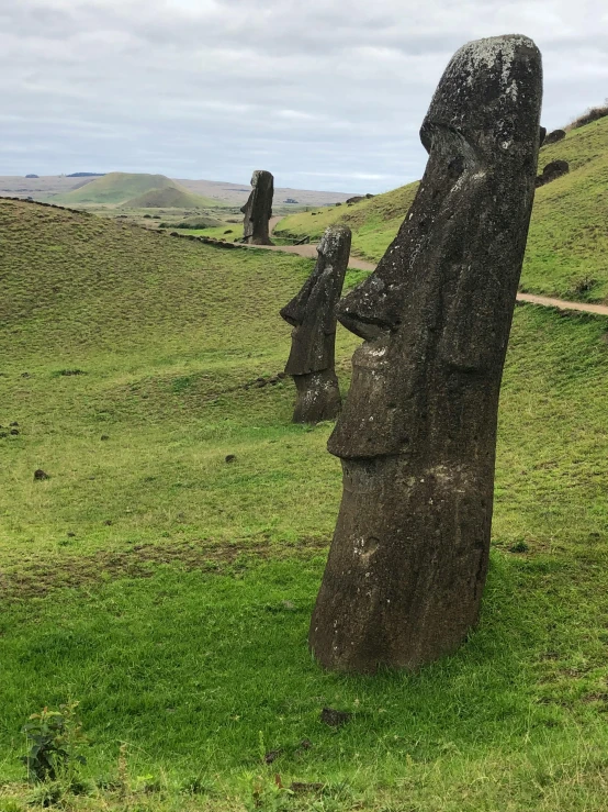 several large statues in a field with hills behind