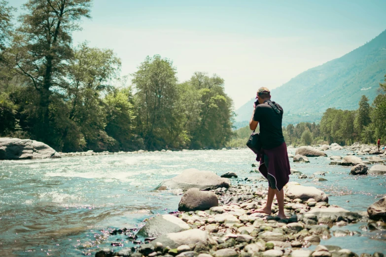 a woman with her backpack in the water near rocks