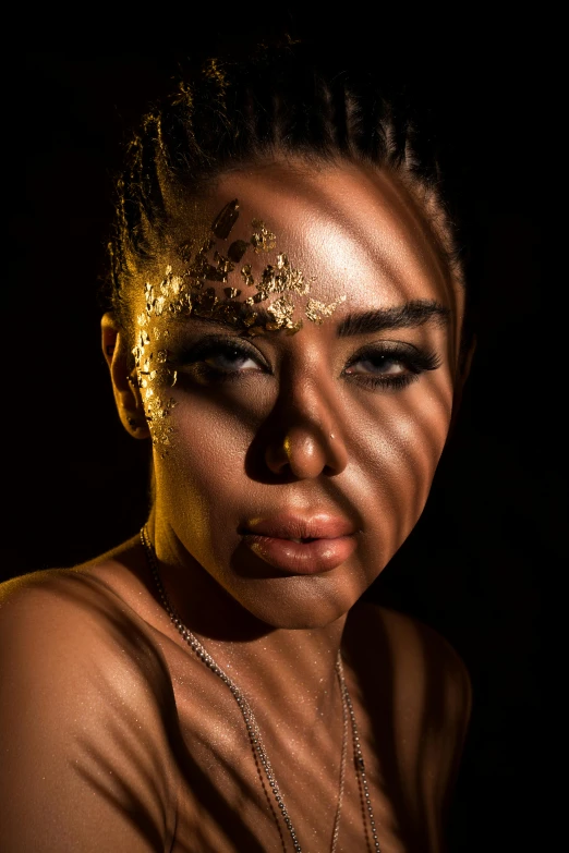 a close up po of a young woman with golden glitter on her face