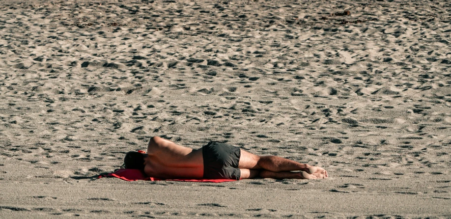 a man laying in the sand and watching soing