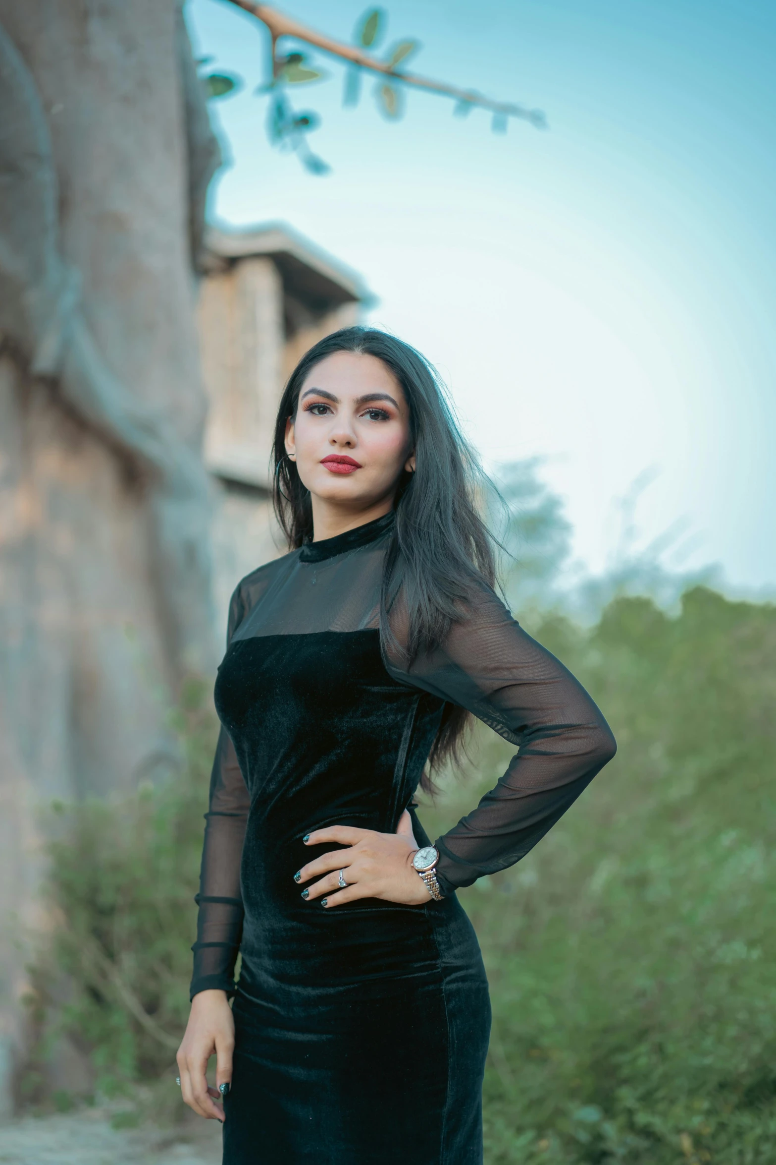 a woman is standing outside, wearing a black dress