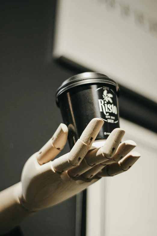 a persons hand holding a plastic cup of coffee