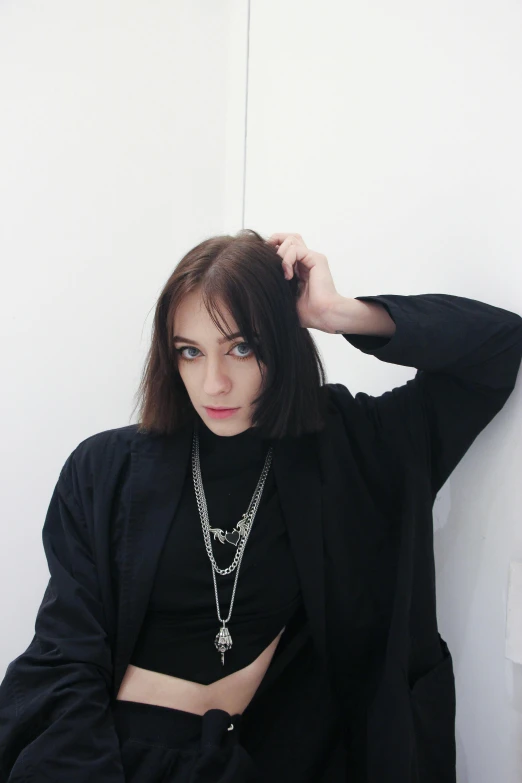 a woman is wearing an open top shirt and is leaning against a wall