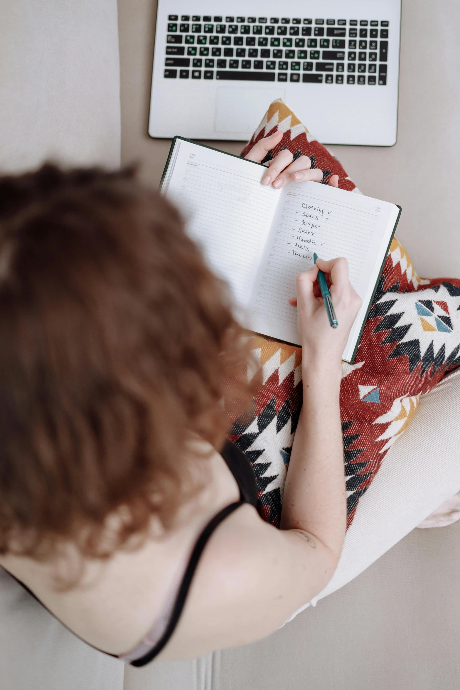 someone on a sofa with a laptop and an open notebook