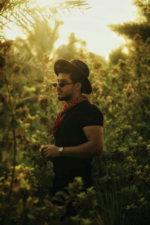 a man wearing sunglasses and a bandana walking in a forest