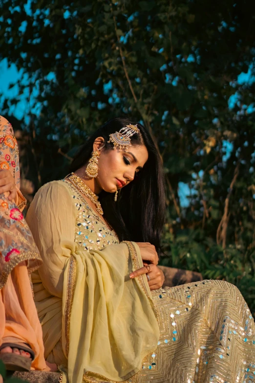 a woman with dark hair wearing jewelry sitting on the ground