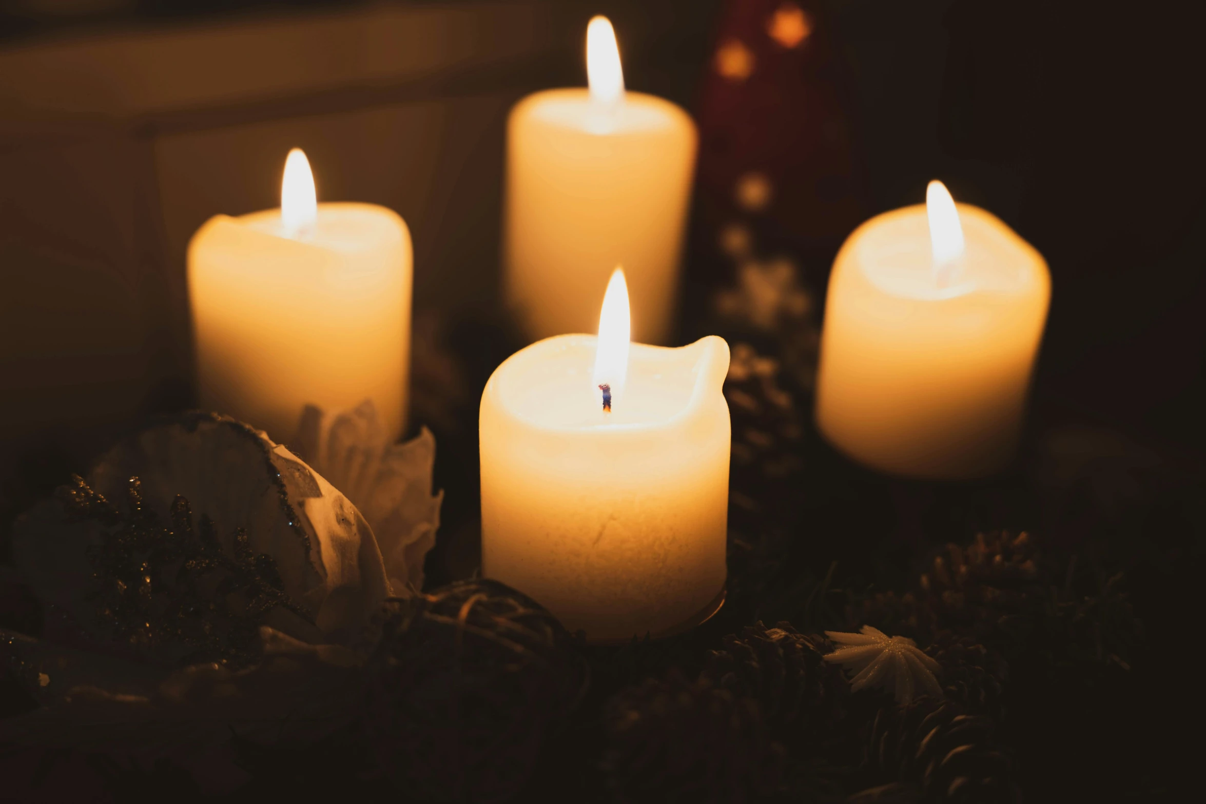 candles with a bunch of white flowers and pine cones