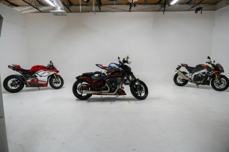 three motorcycles lined up in a white room