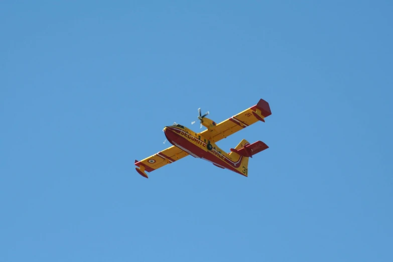 a yellow plane flies through a blue sky