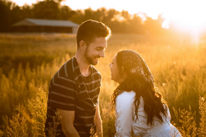 two people are standing in a field and a sun goes down