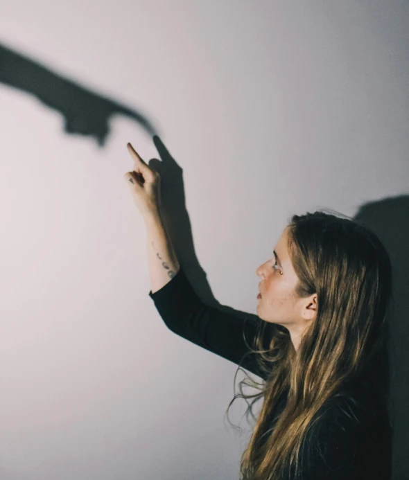 a woman is pointing to a light on a wall