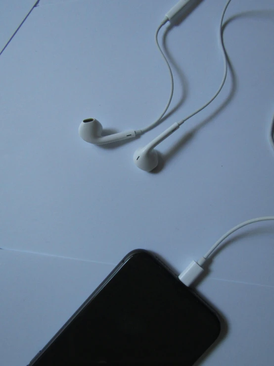 a table with two phones and ear buds and a mouse