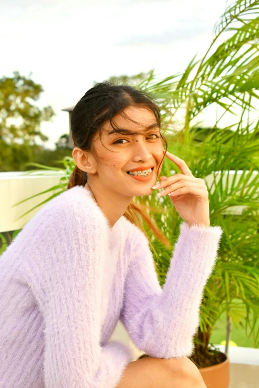 a woman with an expression sitting on the ground in a pink sweater