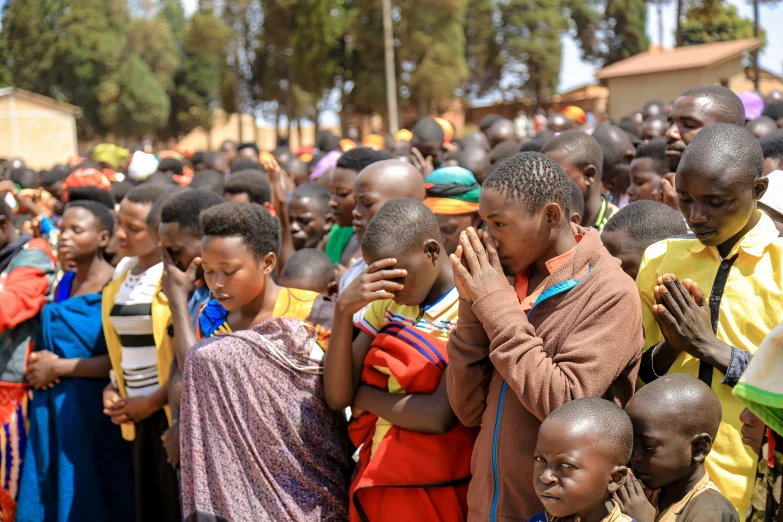 large group of children in orange and blue in a rural area