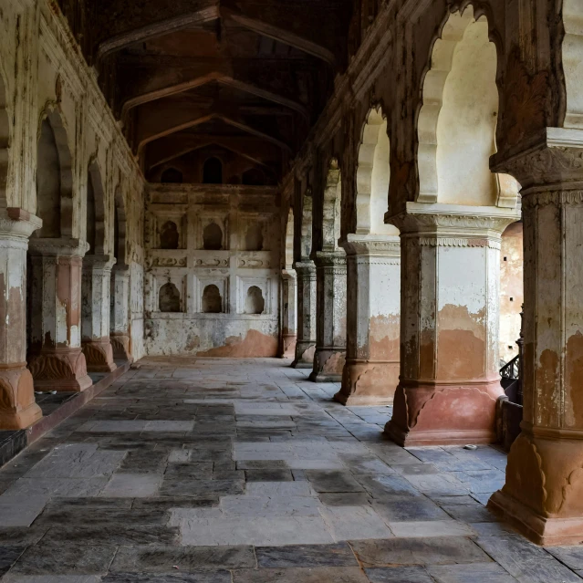 a hallway between a building with columns and tables