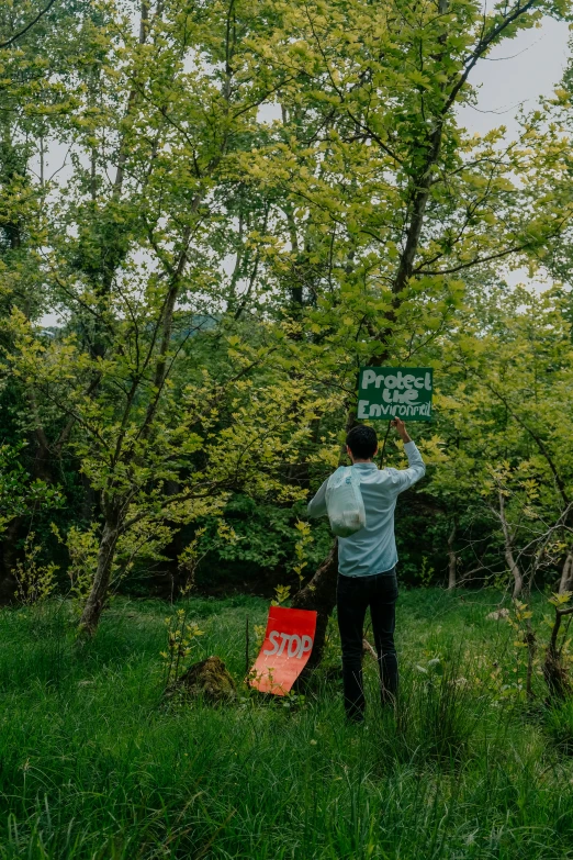 a man is holding up a sign in the grass