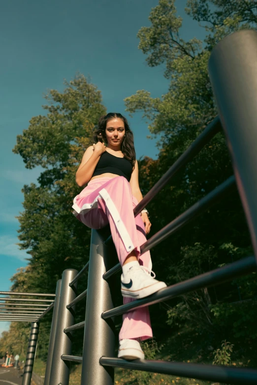 a woman wearing pink is posing on a metal railing