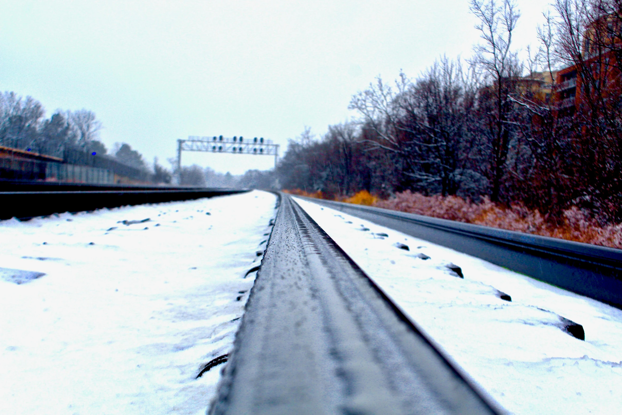 the long train tracks are empty as snow begins to grow