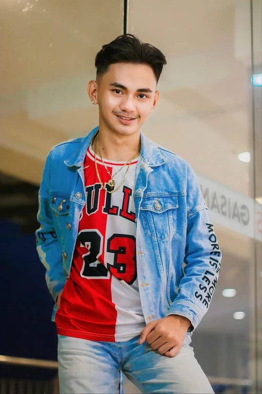 young man in blue denim jacket smiling for po