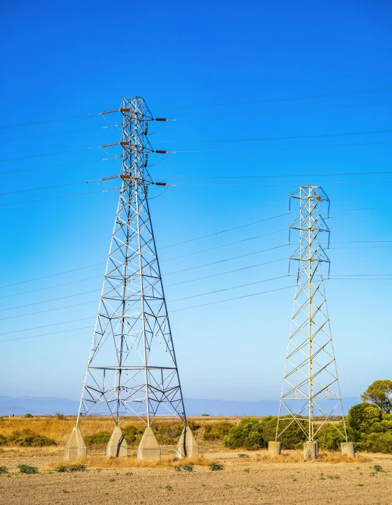 three electricity towers are seen in the desert