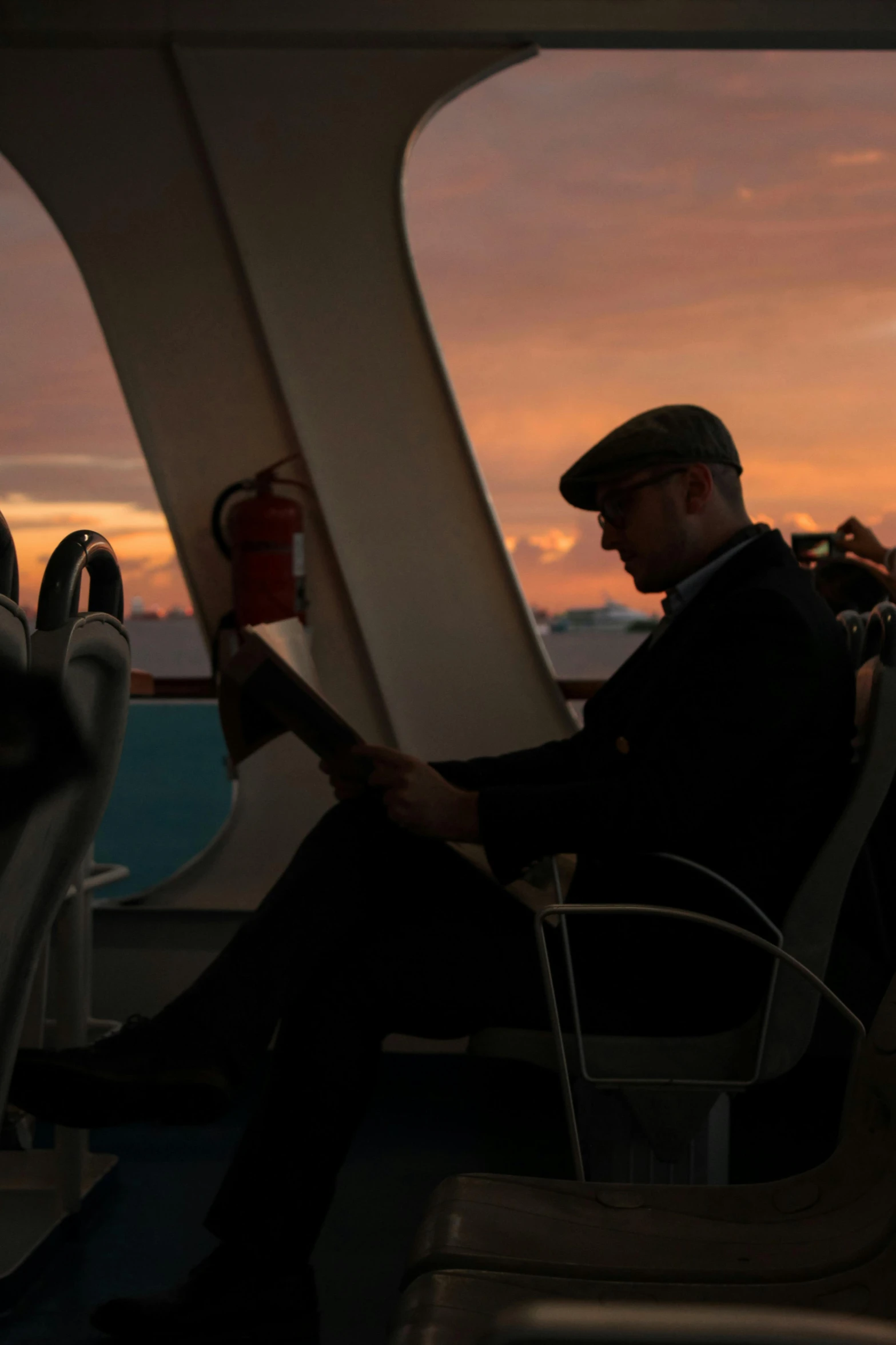 a man sitting on top of a passenger boat holding an airplane book