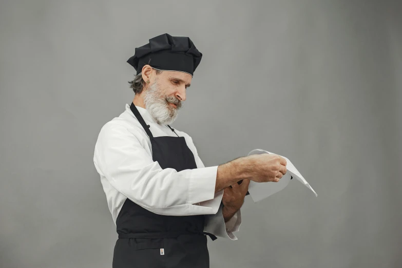 a man dressed in a white and black outfit holds papers and scissors