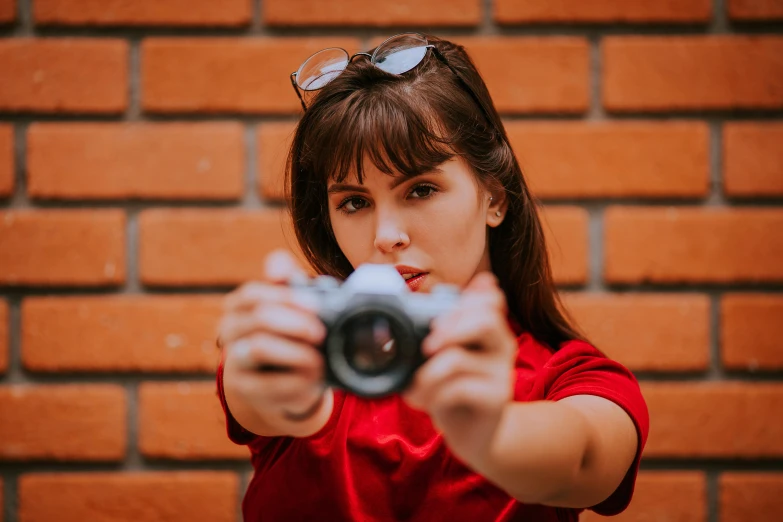 woman wearing sunglasses takes picture with a camera