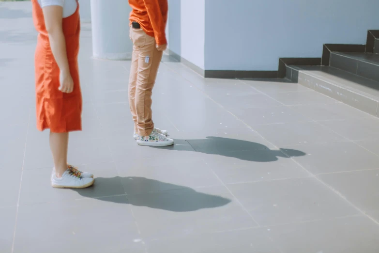 two girls stand in front of stairs in orange dresses