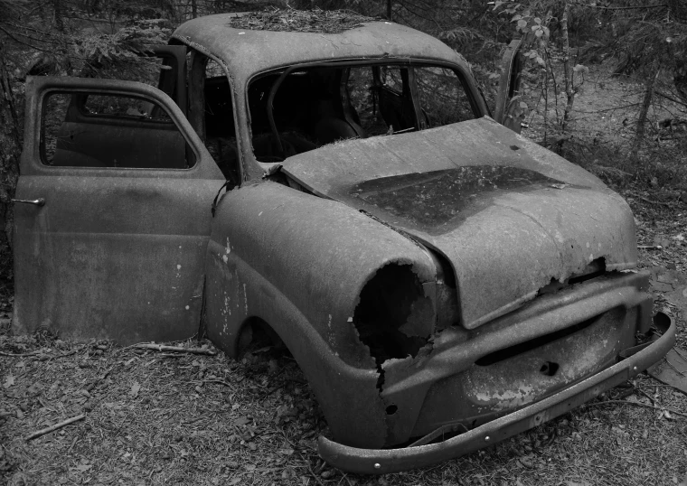 an old truck sitting in the woods with it's front end smashed