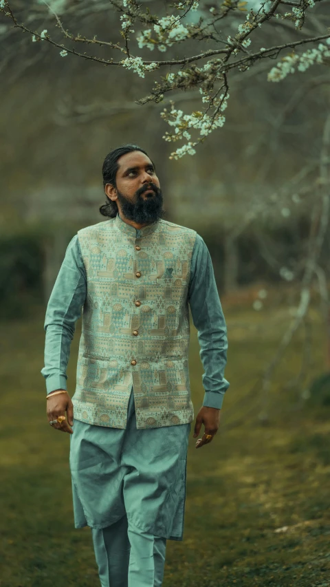 a man in a blue shirt standing next to white blossoming tree