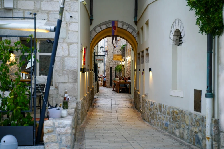 there are several flowers and a clock in the alley way