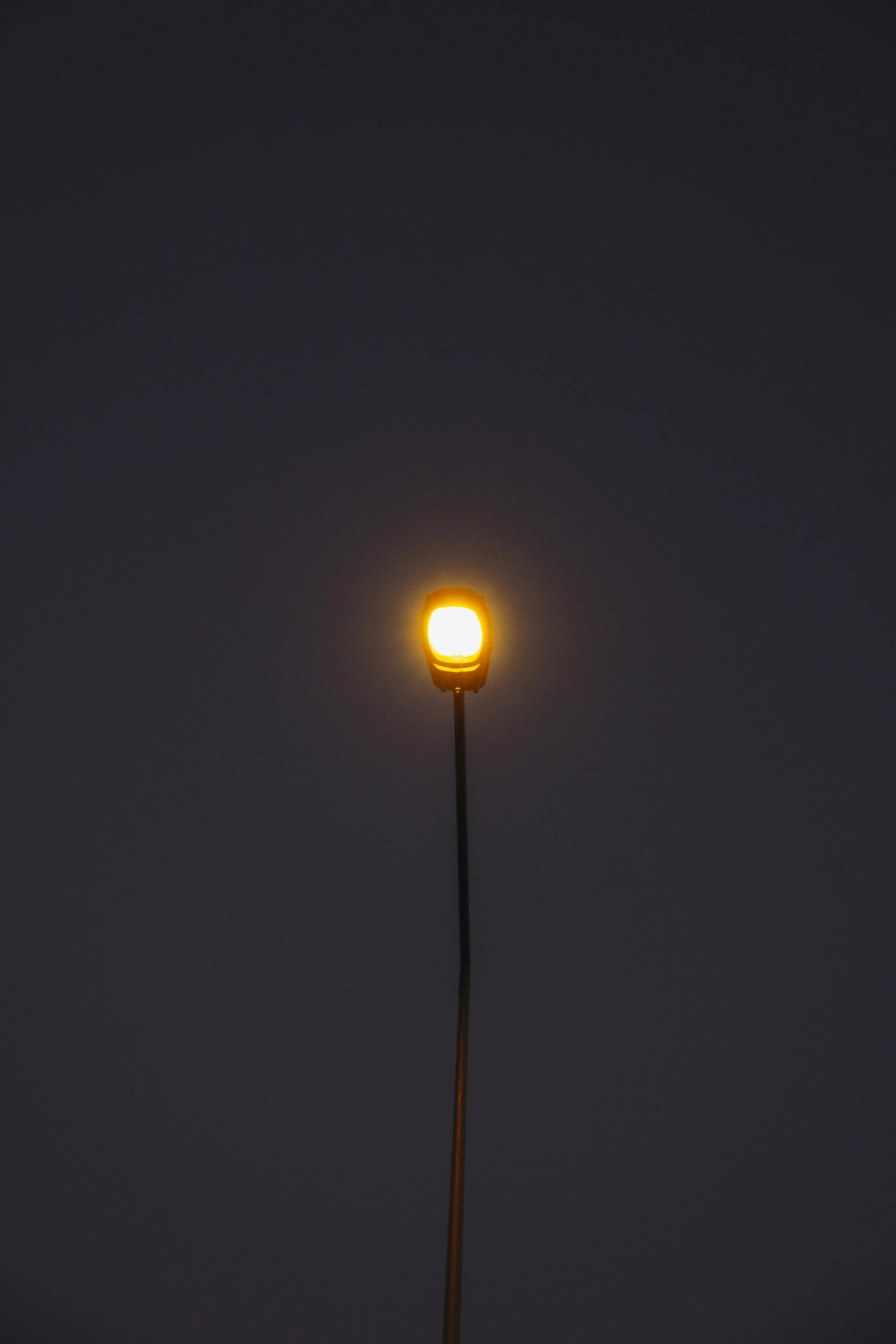 a street lamp is lit at night, in the background a dark sky