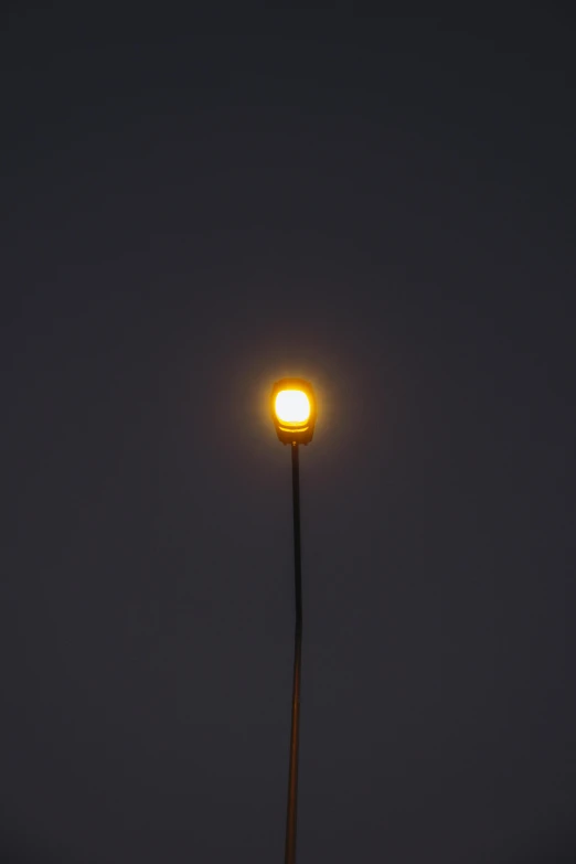 a street lamp is lit at night, in the background a dark sky