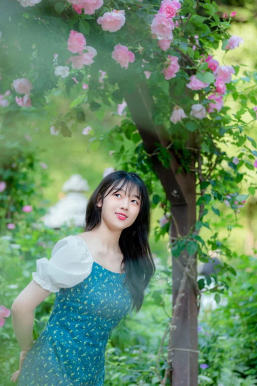 a girl poses in front of flowers with green foliage