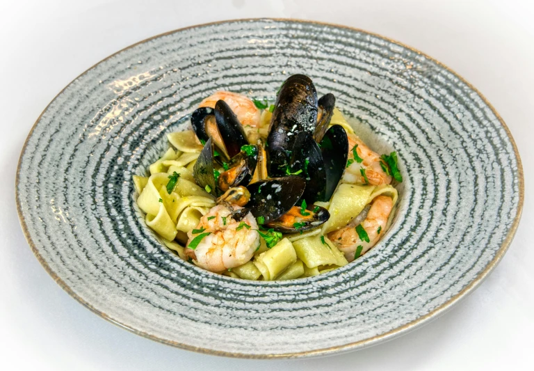 a dish with two clams and noodles on a blue plate