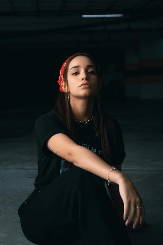 a young woman is sitting in the dark with her eyes closed