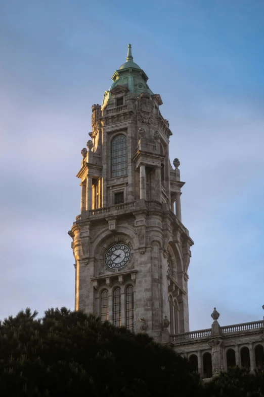 a tall building with a very large clock tower next to trees