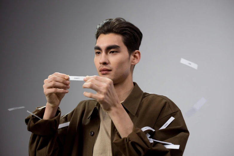 a young man smoking a cigarette near a wall