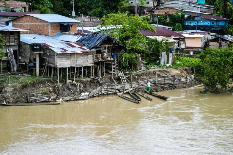 a wooden hut on stilts next to the river with people out front