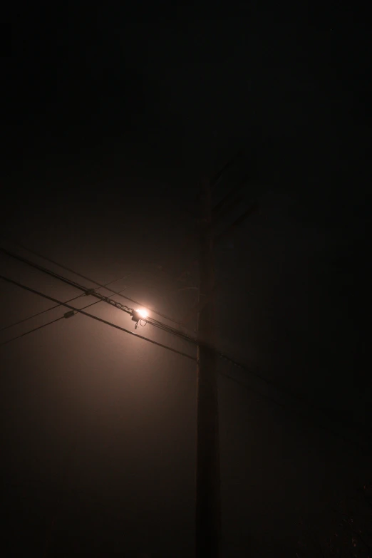 a street light shining on the dark, overcast night