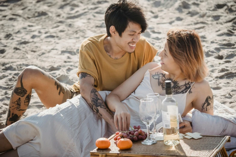 two people eating on the beach in a sunny spot