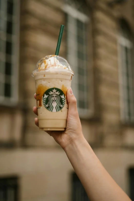 a person holding an iced cup with whipped cream