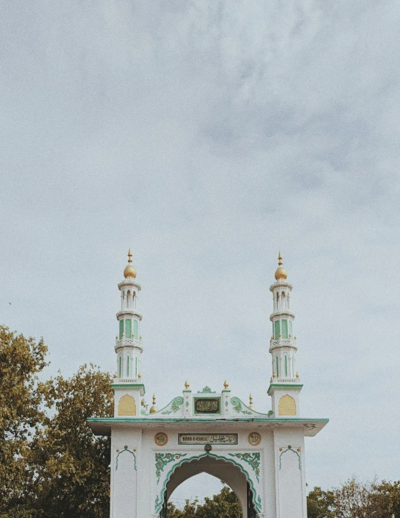 a very large white and green gate with gold top domes