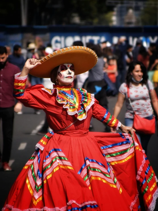 a woman wearing colorful dress and big hat while walking down the street