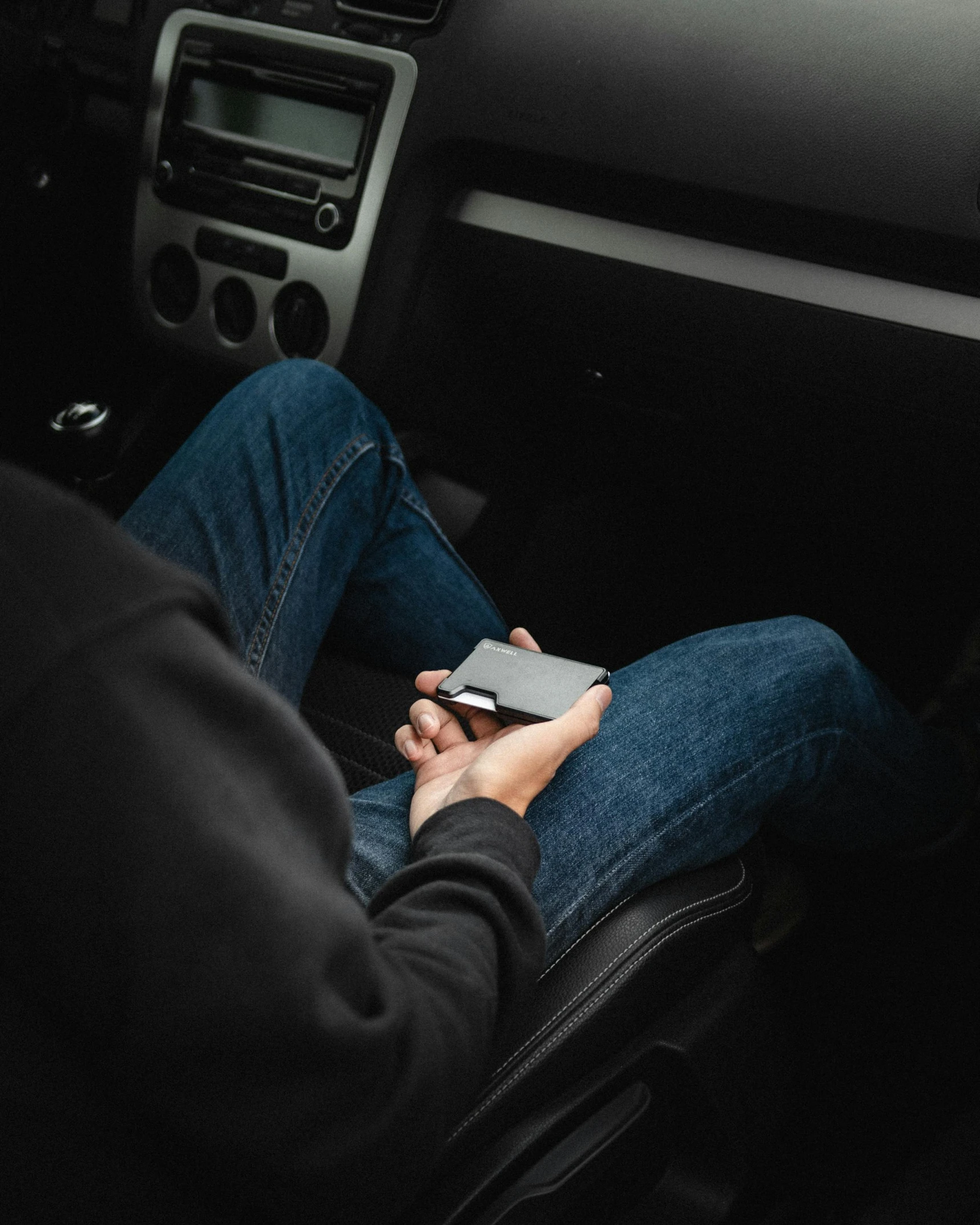 a man sitting in the seat of a car with his cell phone in his hand