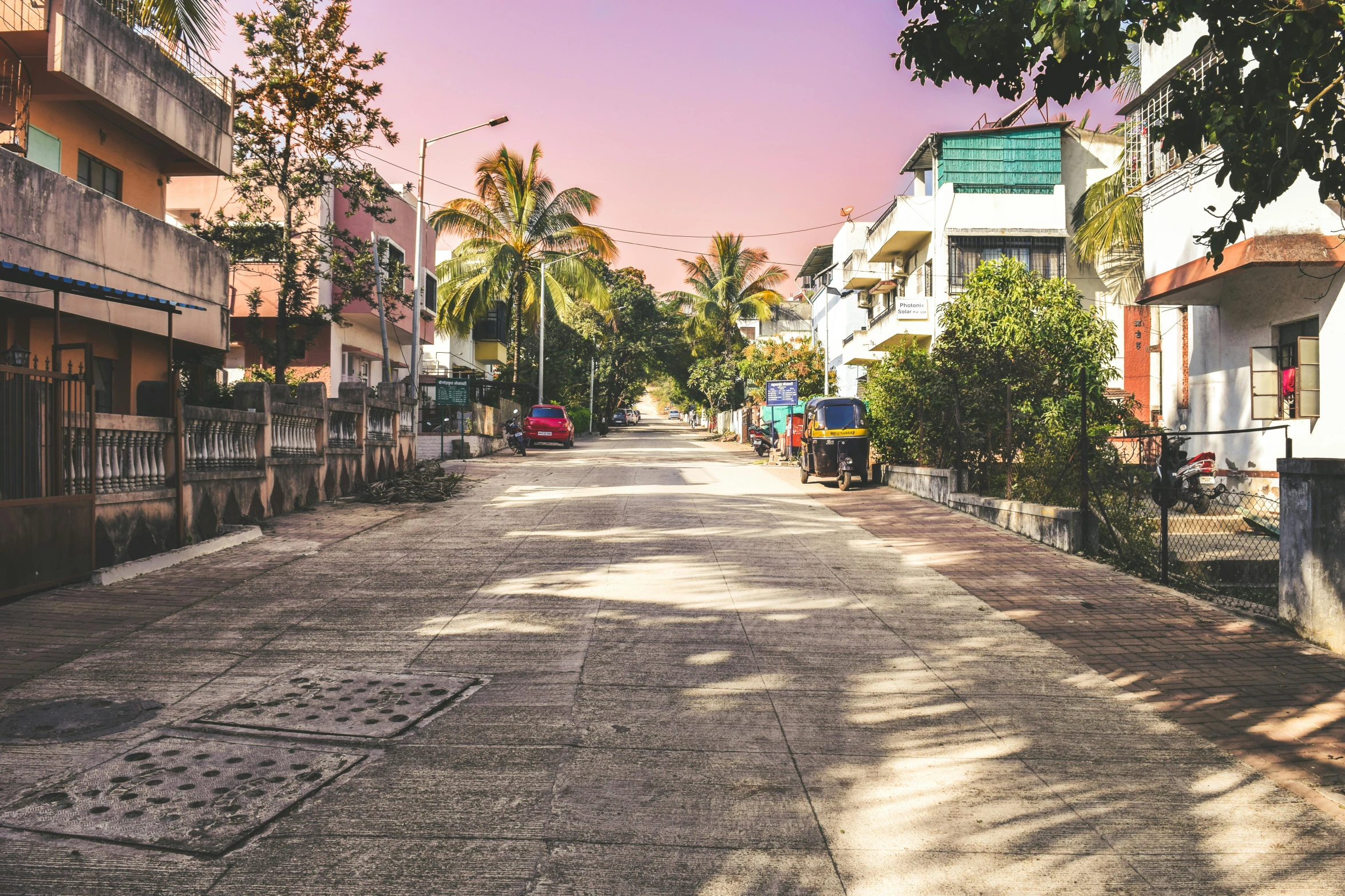 a dirt street lined with buildings and trees